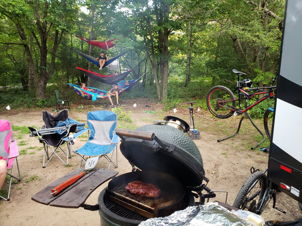 Campsite with grill, lawn chairs, bikes, and hammocks