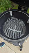 A Spider Huntsman grill with its lid open, showing a 17 inch Kick ash Basket inside. There is 1 to 2 inches of space between the basket and the grill