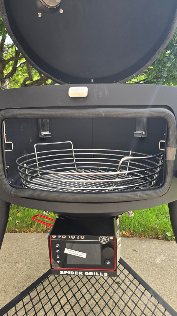 A Spider Huntsman grill with its lid open, showing a 17 inch Kick ash Basket inside. The view is from the side door of the grill.