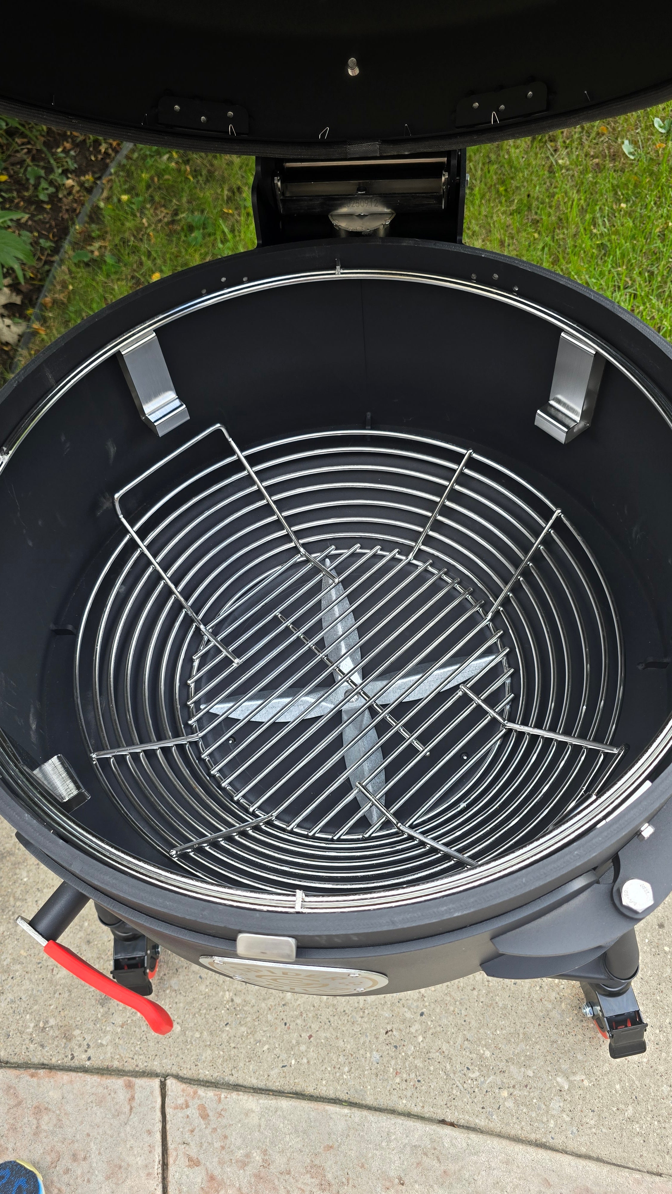 A top-down view of a Spider Huntsman grill with its lid open, showing a Kick Ash Basket inside.  KAB-BKT-C1912