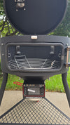 A side view of a Spider Huntsman grill with its lid open, showing a Kick Ash Basket inside.  The basket is KAB-BKT-C1912